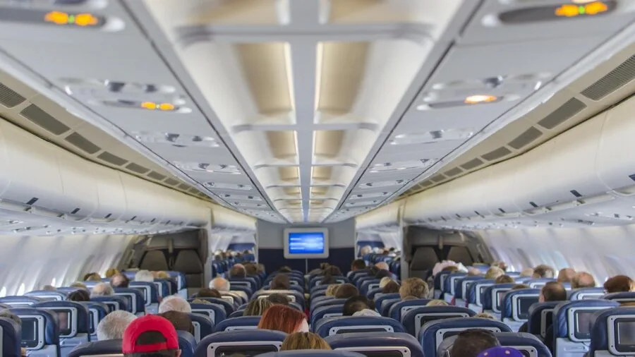 Person checking carry-on luggage size against airline overhead compartment during airport travel