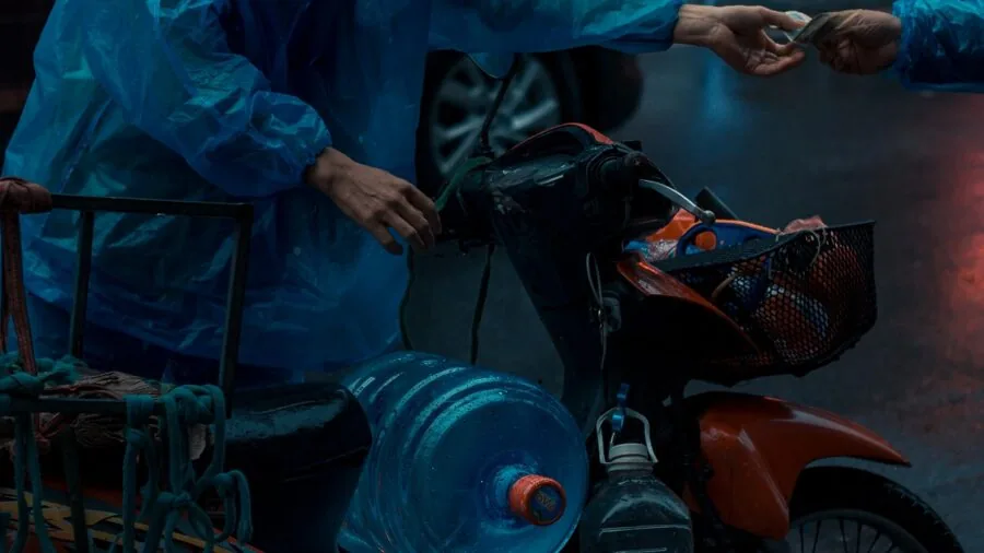 Person checking water bottle for leaks near backpack and laptop in casual setting
