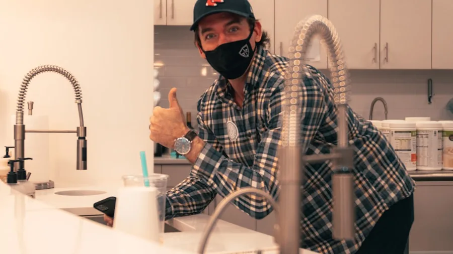 Person cleaning and maintaining a coffee maker at the kitchen sink with water and cloth
