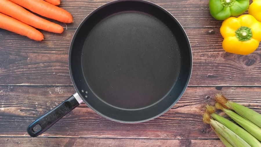 Person cooking with nonstick pan in modern kitchen during meal preparation