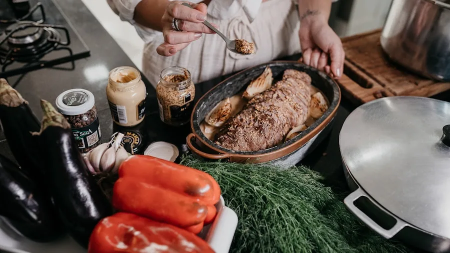 Person cooking with stainless steel cookware on stovetop in bright kitchen