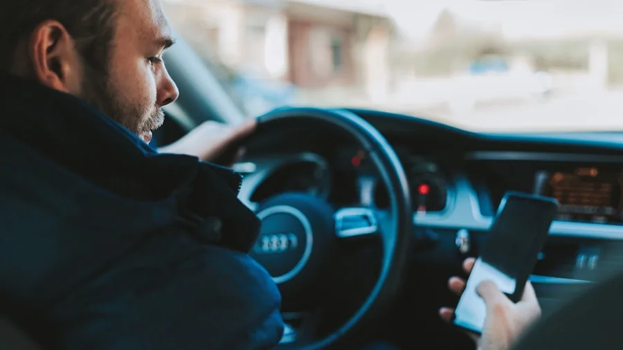 Person driving car with smartphone mounted on dashboard during daytime commute