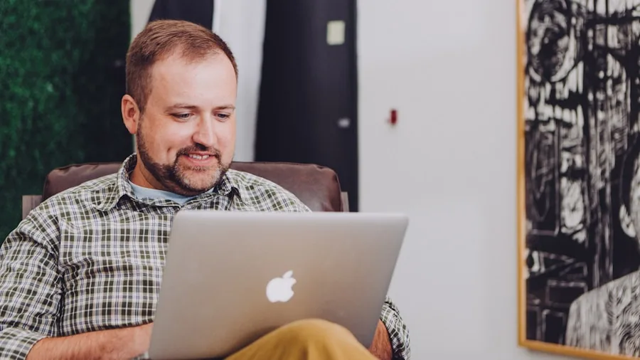 Person editing photos on laptop at wooden desk with natural lighting and coffee cup nearby