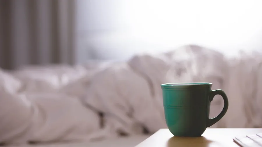 Person enjoying a comfortable bed with soft bedding and pillows in natural morning light