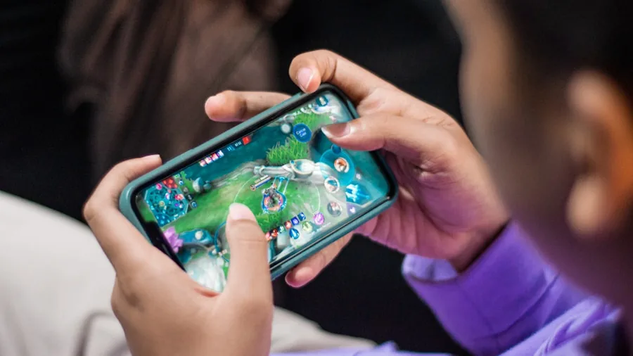 Person enjoying mobile gaming on smartphone with focused, immersed expression in comfortable setting