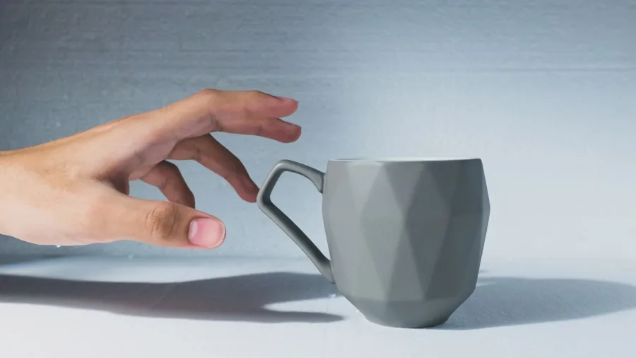 Person examining a broken travel mug, checking the lid and body for damage in a home setting