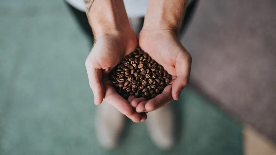 Person examining coffee beans while comparing prices and quality options at home