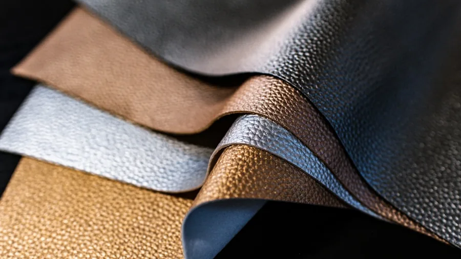 Person examining leather material texture with hands, showcasing natural grain and quality details