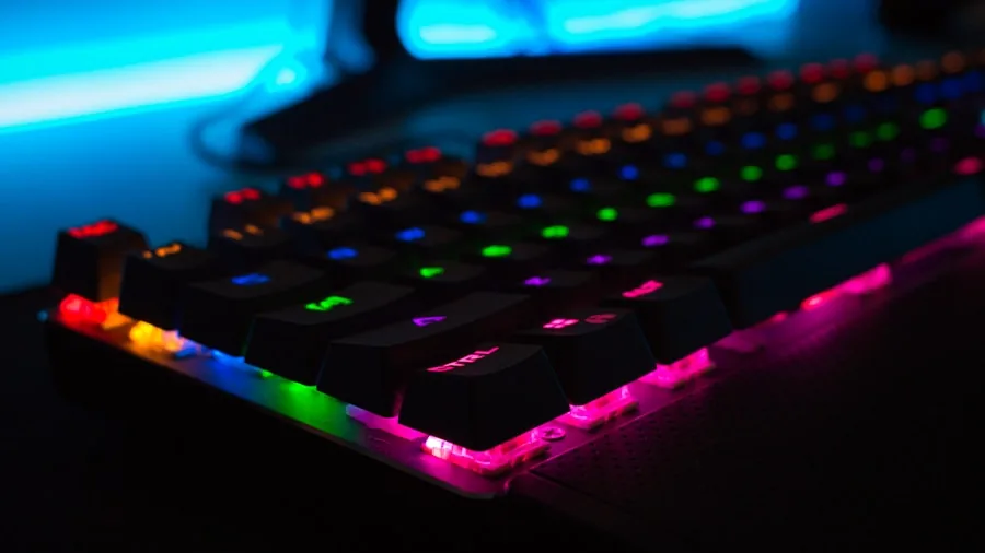 The %product_count% Best Gaming Keyboards 4 Person gaming at desk with vibrant RGB keyboard lighting in dark room environment