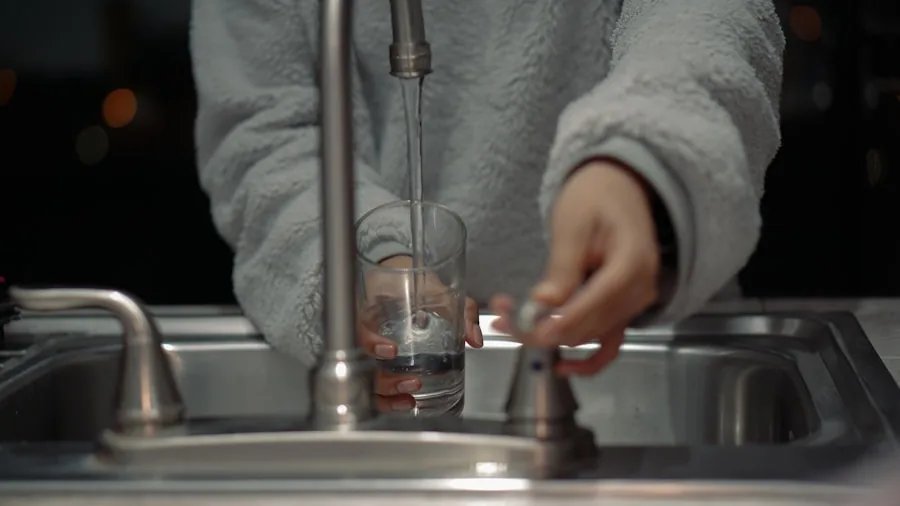Person hand-washing a travel mug at kitchen sink with warm water and soap