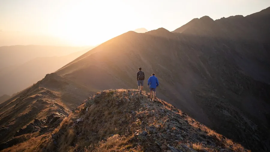 Person hiking on exposed mountain ridge in windy conditions wearing protective outerwear