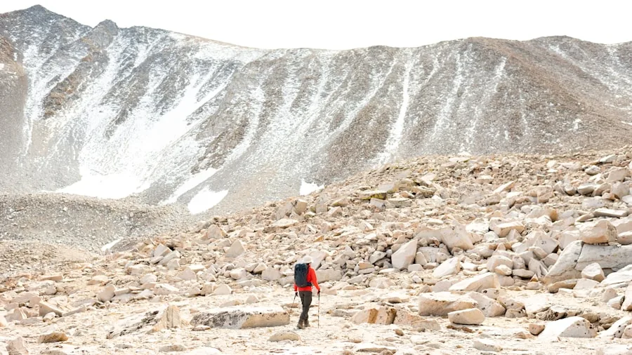Person hiking through rugged mountainous terrain with rocky ground and elevation changes