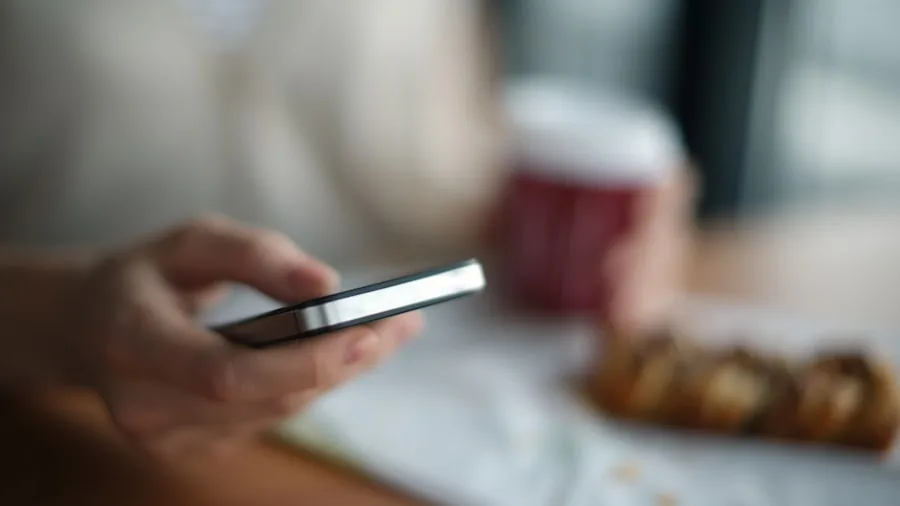 Person holding mobile device comfortably while reading, demonstrating ergonomic grip and weight distribution