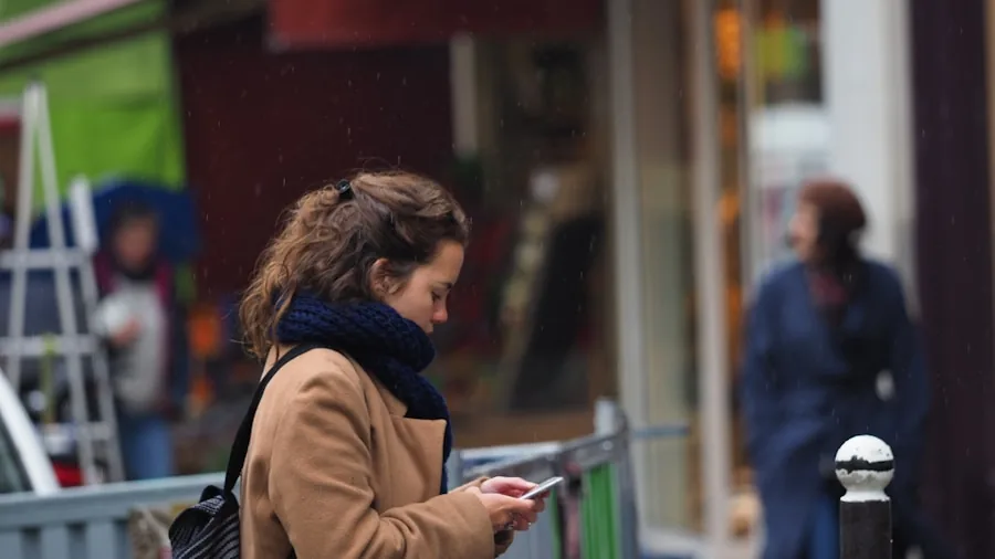 The %product_count% Best Budget Phones 5 Person holding smartphone in rainy outdoor environment, demonstrating water resistance during everyday use