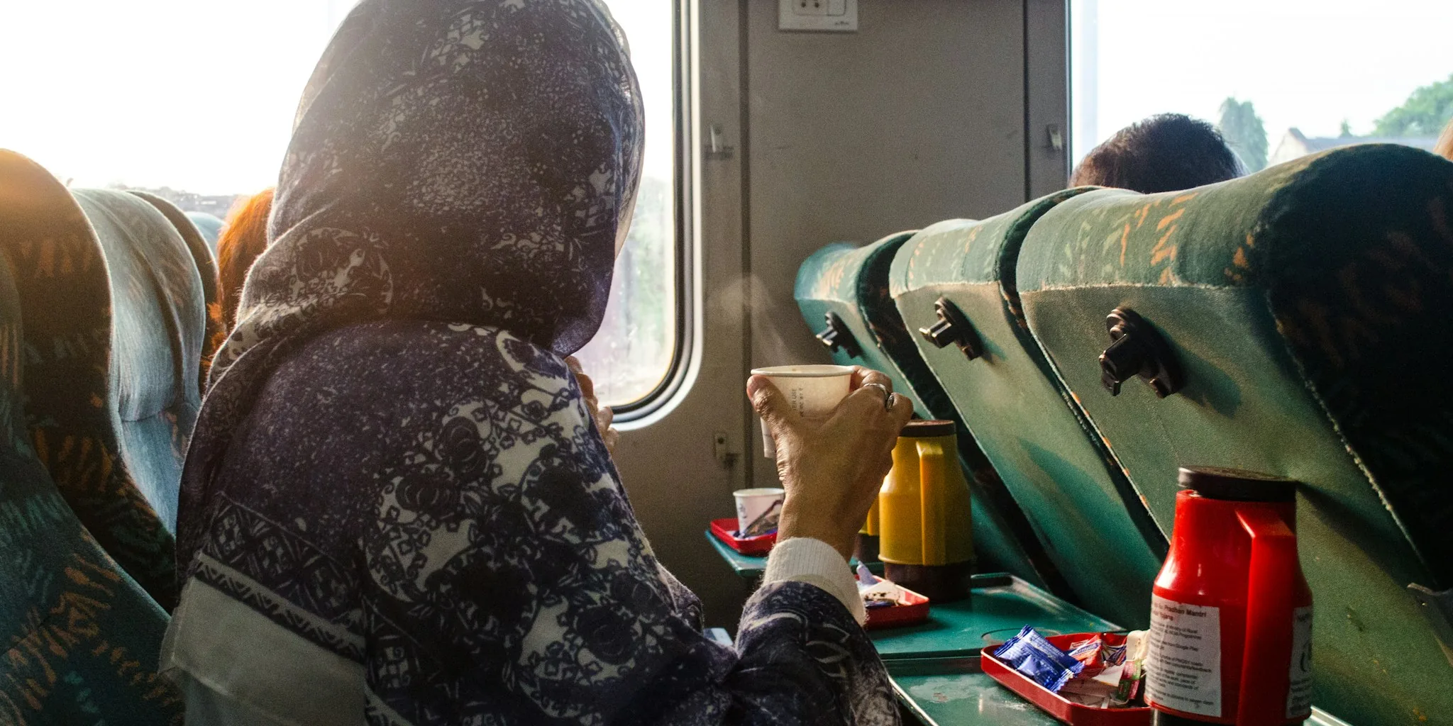 Person holding travel mug while traveling on train or commuting to work