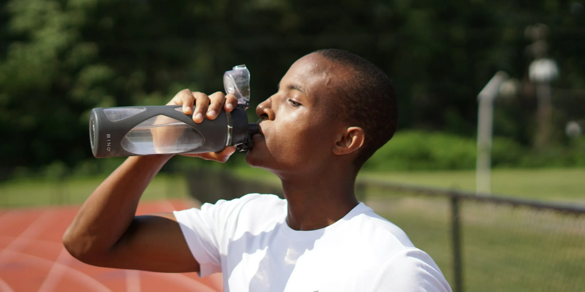 Person hydrating with water bottle during outdoor exercise training session
