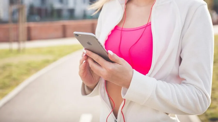 Person in athletic wear checking phone during outdoor fitness session