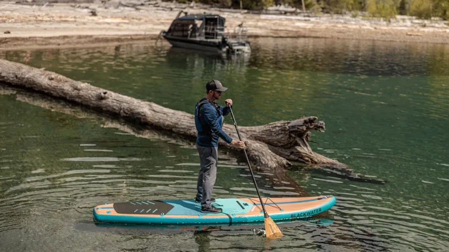 Person inflating a paddle board by the water before a day of paddleboarding on the lake