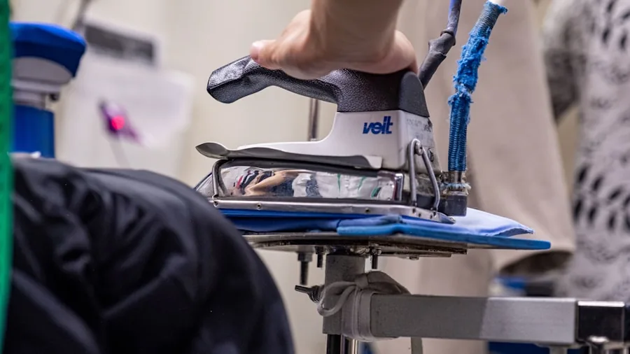 Person ironing clothes on ironing board, focused on hand position and technique during laundry task