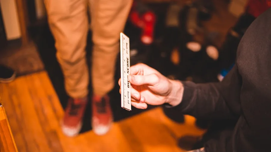 The %product_count% Best Skate Shoes 4 Person measuring their foot length with a ruler on a wooden floor at home
