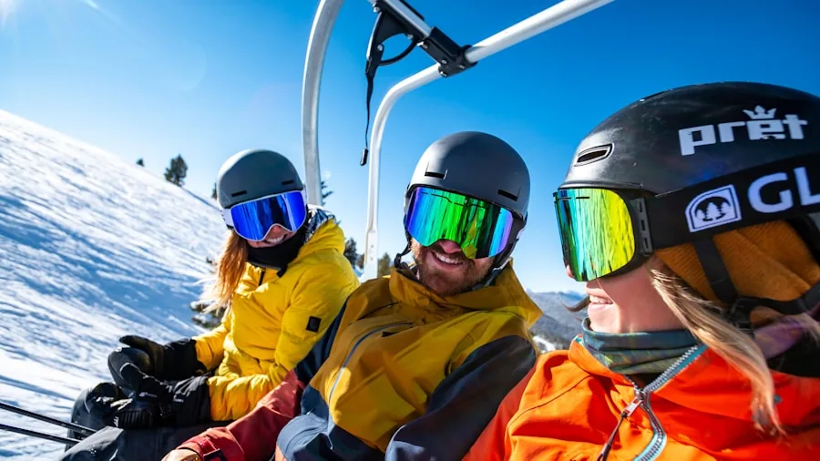 Person on ski lift enjoying winter mountain scenery with snowy peaks in background