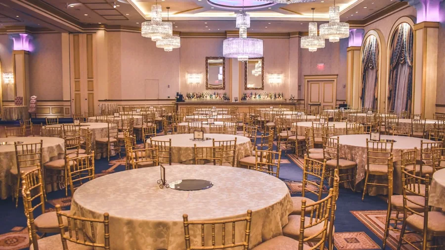 Person organizing stacked chairs for large event setup in empty venue hall
