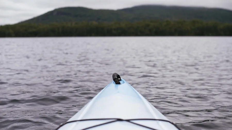 The %product_count% Best Kayaks for Fishing 5 Person performing maintenance on kayak by lakeside, cleaning and inspecting hull durability