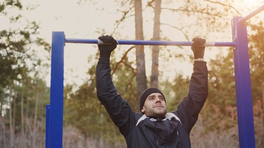Person performing pull up exercise on outdoor bar in natural setting