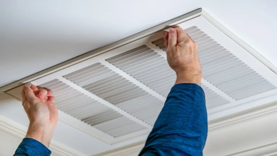 Person performing routine home air filter maintenance and cleaning in residential living space