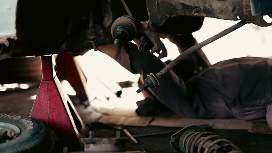 Person performing vehicle maintenance work under car engine area in garage setting