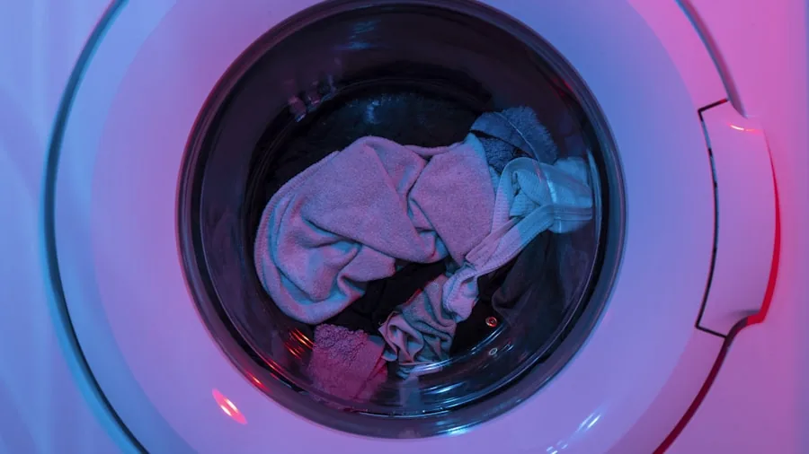 Person placing clothes into a front-load washing machine during laundry day