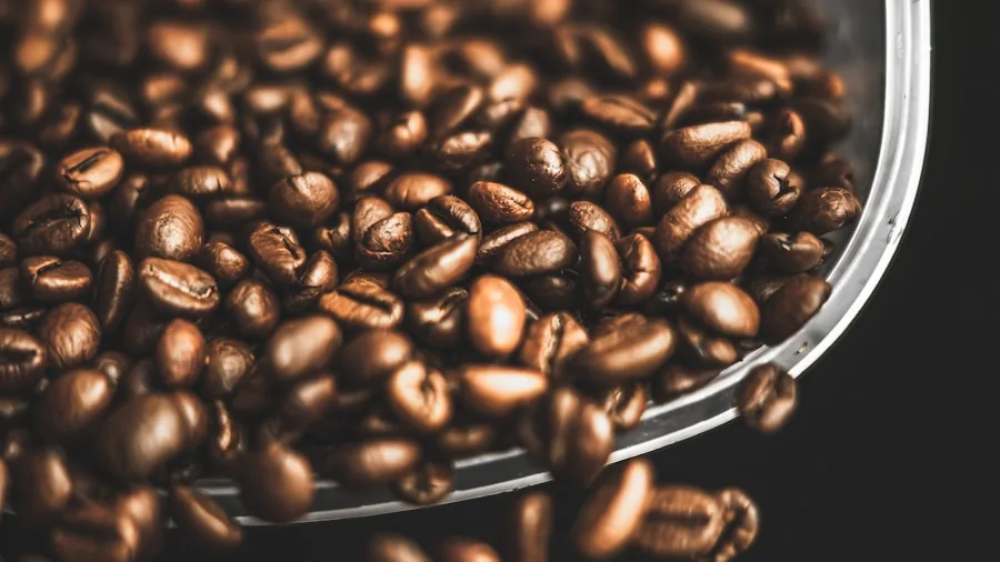 Person pouring freshly roasted coffee beans into a cup for brewing