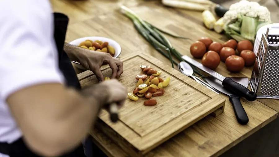 Person preparing diverse foods in a modern kitchen, demonstrating cooking versatility and meal preparation techniques