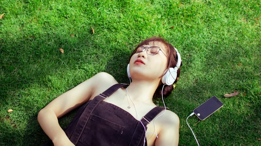 Person relaxing outdoors while listening to music with a portable speaker in a natural setting