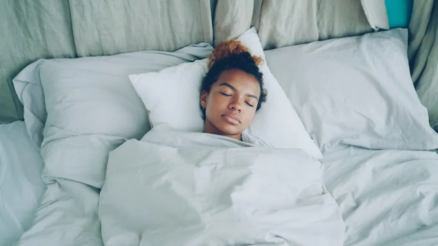 Person resting comfortably under blanket on bed at night