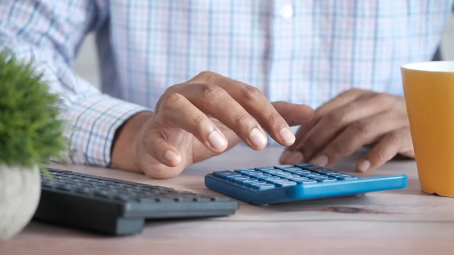 Person reviewing financial documents and calculator to evaluate long-term investment costs and budgeting decisions