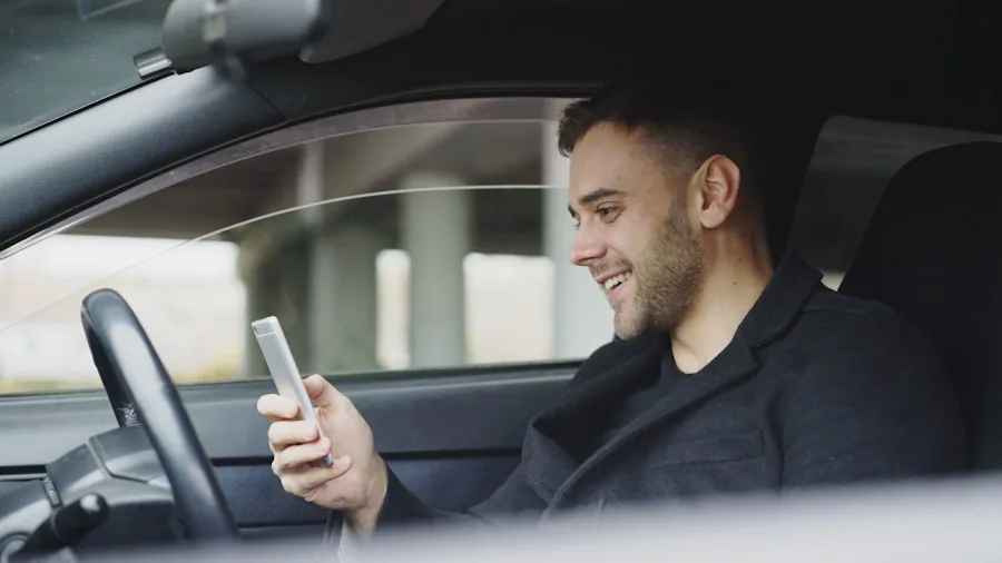Person safely mounting smartphone on car dashboard while driving, hands-free navigation setup in vehicle interior