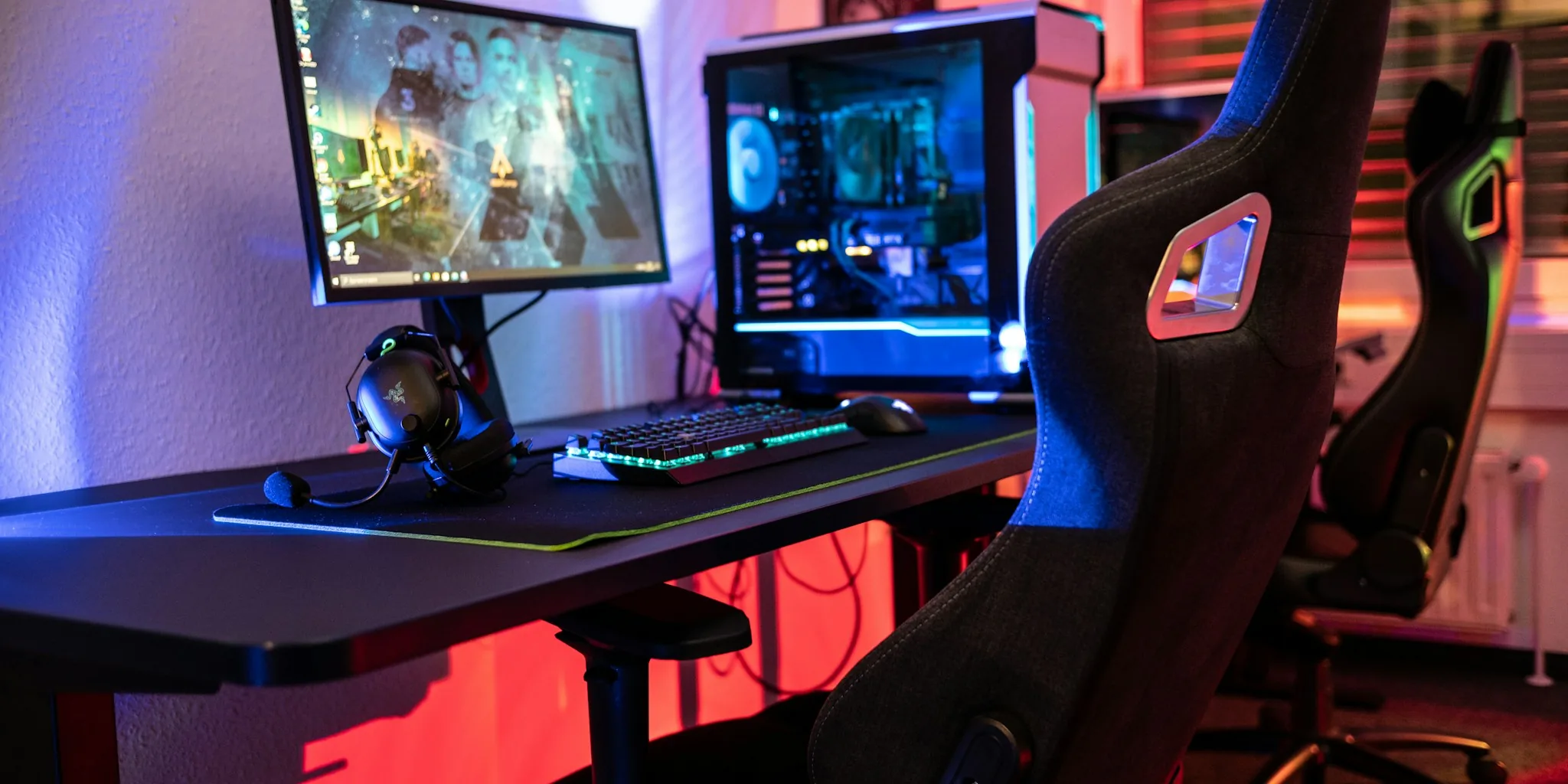 Person seated in gaming chair at desk with multiple monitors during gaming session
