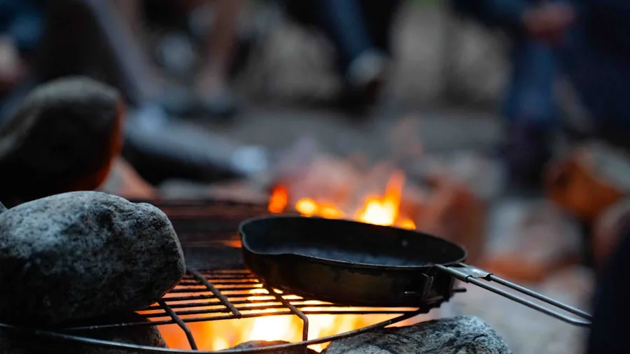 Person setting up compact grill at campsite in natural outdoor setting