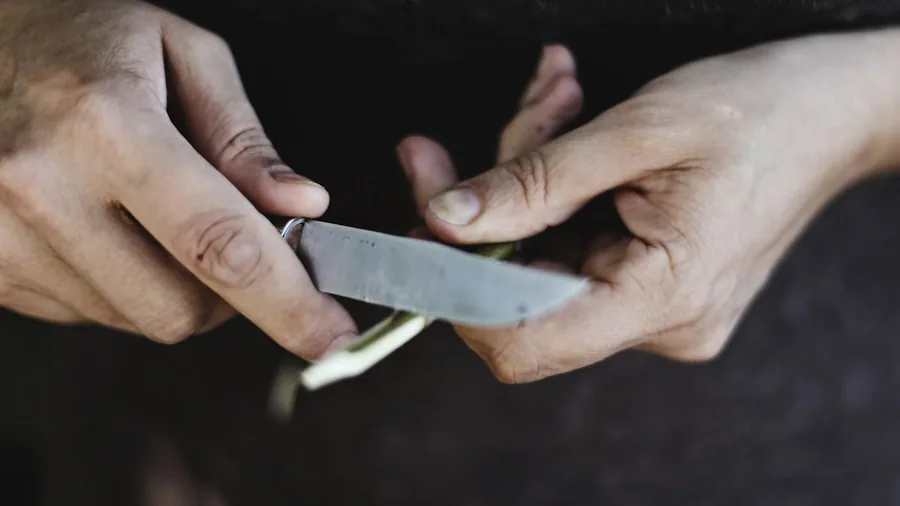 The %product_count% Best Knife Sharpeners 4 Person sharpening a kitchen knife by hand over a wooden cutting board in a home kitchen