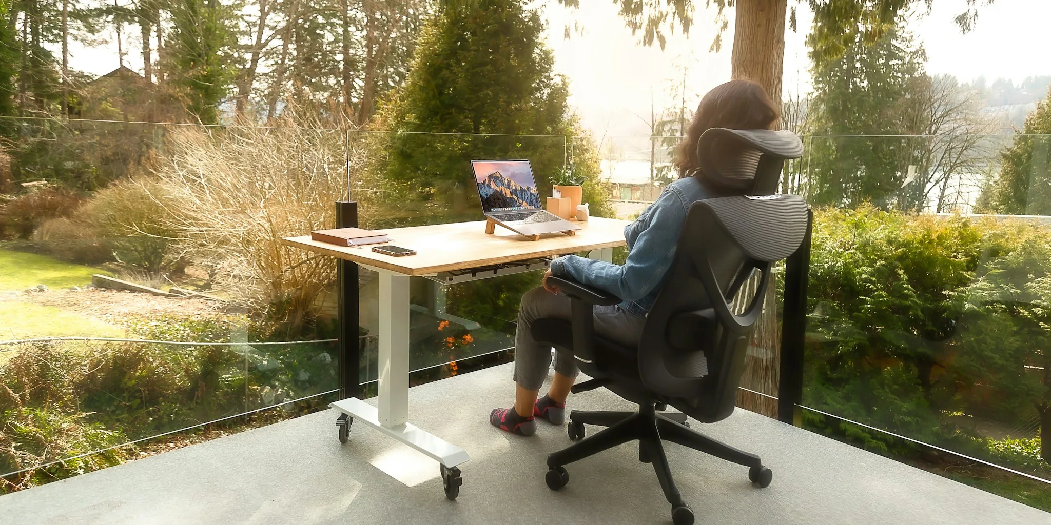 Person sitting at desk in ergonomic chair while working on computer in bright home office