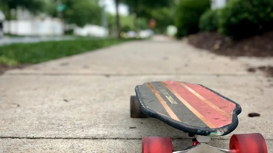 Person skateboarding outdoors on smooth ground, demonstrating smooth rolling motion and board performance