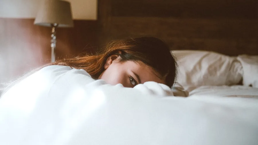 Person sleeping peacefully on a comfortable bed with quality bedding and pillows