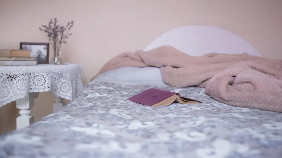 Person smoothing fitted sheets on bed during morning routine
