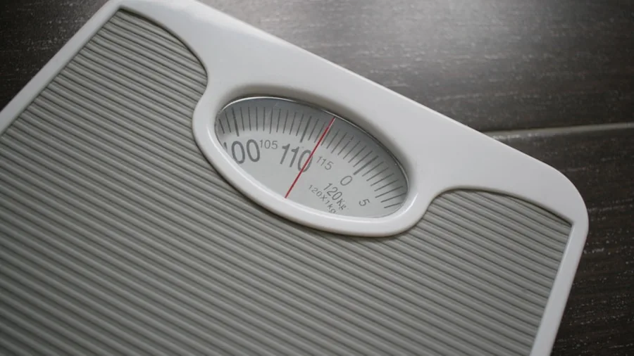Person standing on bathroom scale in modern bathroom for daily weight monitoring routine