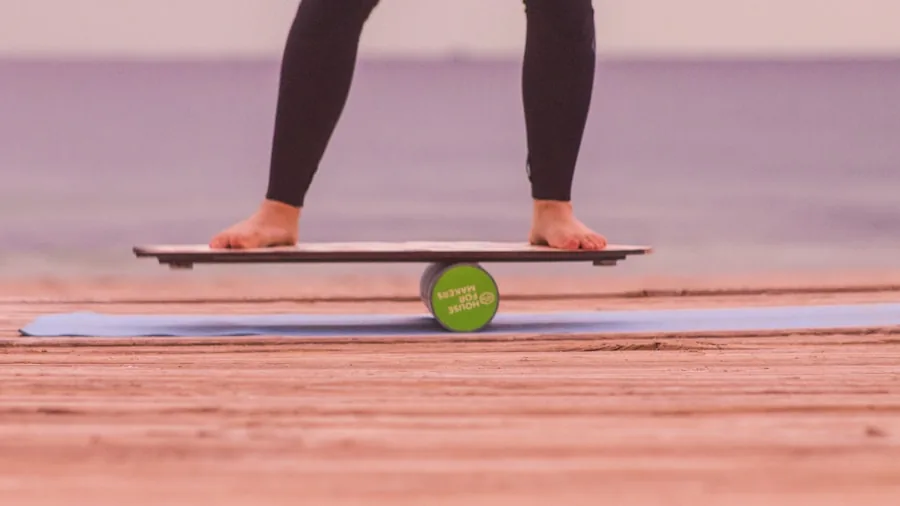 Person standing on wide paddle board in calm water, learning proper stance and balance