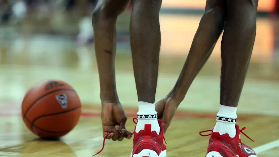Person trying on basketball shoes, examining fit and comfort during shopping