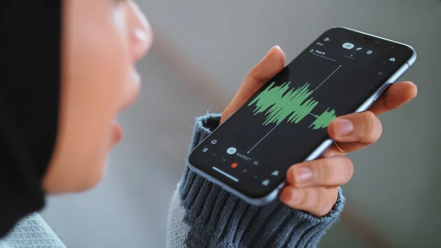 Person using smartphone app to control home audio system settings while watching TV