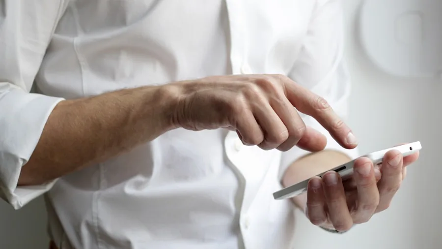 Person using smartphone app to control home temperature and smart devices from living room