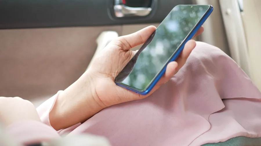 Person using smartphone mounted in car for navigation while driving safely on road